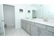 Bright bathroom featuring dual sinks, gray cabinets, and marble-look tile flooring at 976 Leader St, Davenport, FL 33896