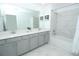 Bathroom featuring double vanity, marble tile accents, and combined shower and bathtub at 976 Leader St, Davenport, FL 33896