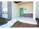 Inviting covered front porch with a bright green door and stylish stone accents at 976 Leader St, Davenport, FL 33896
