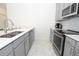 Charming kitchen featuring stainless steel appliances, gray cabinets, and white countertops and backsplash at 976 Leader St, Davenport, FL 33896