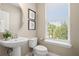 Contemporary powder room featuring pedestal sink, round mirror, and a window with a view at 13618 Heaney Ave, Orlando, FL 32827