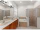 Neutral tone bathroom with double sinks, soaking tub, and a glass-enclosed shower at 13768 Bluebird Pond Rd, Windermere, FL 34786