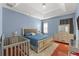 Comfortable blue bedroom with wood floors, a tray ceiling, a large bed, and a gray baby crib at 13768 Bluebird Pond Rd, Windermere, FL 34786