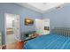 Cozy bedroom with a blue accent wall, wood floors, and an open view to a bathroom with a tub at 13768 Bluebird Pond Rd, Windermere, FL 34786