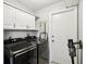 Well-lit laundry room features modern, front-loading washer and dryer with white cabinets above at 14565 Lycastle Cir, Orlando, FL 32826