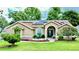 Charming single-story home featuring well-manicured lawn, mature trees, and solar panels on the roof at 14723 Pine Cone Trl, Clermont, FL 34711