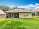 The backyard features lush green grass, a well-maintained lawn, and a screened-in patio at 16631 Champions Ct, Clermont, FL 34711