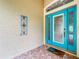 Bright turquoise front door with glass panels and decorative side panel on covered porch at 16631 Champions Ct, Clermont, FL 34711