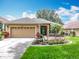 Charming home featuring a lush lawn, a well-maintained garden, and a two-car garage at 16631 Champions Ct, Clermont, FL 34711