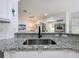 Modern kitchen sink and granite countertop overlooking the living room and outdoor patio at 16631 Champions Ct, Clermont, FL 34711