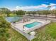 Community pool and tennis courts with lounge chairs, fence, and well-maintained landscape at 16631 Champions Ct, Clermont, FL 34711