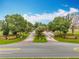 Community entrance with lush trees and manicured landscaping on a bright day at 16631 Champions Ct, Clermont, FL 34711