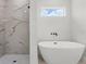 Bathroom showcasing tile shower with black fixtures and free standing tub beneath window at 17485 Sw 41St Cir, Ocala, FL 34473
