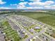 High aerial view of a planned community with houses, streets, a pool, and agricultural land in the distance at 1854 Juneberry St, Clermont, FL 34715