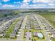 Wide aerial shot of a neighborhood featuring orderly homes, streets, a community pool, and vast farmland at 1854 Juneberry St, Clermont, FL 34715