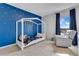Cozy bedroom with blue accent wall and unique bedframe, window with neutral curtains, and a glider at 1854 Juneberry St, Clermont, FL 34715