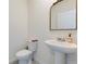 Bright half-bathroom featuring a pedestal sink, decorative mirror and toilet at 1854 Juneberry St, Clermont, FL 34715