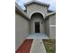 Inviting entryway with a dark wood door, arched alcove, and landscaped flower bed at 304 Lake Daisy Loop, Winter Haven, FL 33884