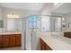 Bright bathroom featuring glass shower doors, dual sinks, and wooden cabinets at 307 Monterey St, Kissimmee, FL 34759
