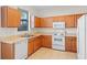 Functional kitchen with wooden cabinets, white appliances, and neutral countertops at 307 Monterey St, Kissimmee, FL 34759