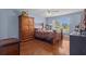 A spacious bedroom with wooden floors, a wooden wardrobe, a bed, and a window overlooking a green landscape at 36646 Oconee Ave, Eustis, FL 32736