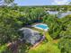 Aerial view of house with pool, fenced yard, and serene lake backdrop surrounded by lush greenery at 4102 Plantation Cove Dr # 201, Orlando, FL 32810