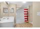 Bright bathroom featuring a clean white vanity, a large mirror, and a shower with a vibrant striped curtain at 4600 Yellowgold W Rd # 102, Kissimmee, FL 34746