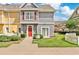 Charming townhome featuring a vibrant red door and neutral gray siding, surrounded by lush green landscaping at 4600 Yellowgold W Rd # 102, Kissimmee, FL 34746