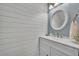 Cozy powder room with shiplap accent wall, white vanity, and round mirror at 5430 Baytowne Pl, Oviedo, FL 32765