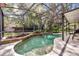 Inviting screened-in pool featuring a stone accent wall and lush landscaping offers a private backyard retreat at 5430 Baytowne Pl, Oviedo, FL 32765
