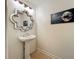 Cozy powder room with a pedestal sink, decorative mirror, and elegant decor at 6336 Buford St # 207, Orlando, FL 32835