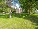 Expansive backyard featuring a well-manicured lawn, mature trees, and a view of the home's exterior at 8330 Lainie Ln, Orlando, FL 32818
