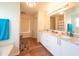 Large bathroom with double sinks, white cabinetry, hardwood floors, and a window at 8330 Lainie Ln, Orlando, FL 32818