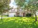 Two-story home featuring a front lawn, a two-car garage, front porch, red shutters, and mature trees at 8330 Lainie Ln, Orlando, FL 32818