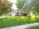 Two-story home featuring a front lawn, a two-car garage, front porch, red shutters, and mature trees at 8330 Lainie Ln, Orlando, FL 32818