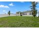 Large backyard with green grass, a white fence, and solar panels on the roof of the house at 884 Laurel View Way, Groveland, FL 34736