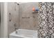 Bathroom tub and shower with gray tile, a curved shower rod, and grab bars for safety and convenience at 884 Laurel View Way, Groveland, FL 34736