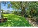 Lush backyard with mature trees, vibrant landscaping, and a well-maintained lawn at 9491 Wickham Way, Orlando, FL 32836