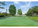 Bright green basketball court with mature trees and a nearby bench at 9491 Wickham Way, Orlando, FL 32836
