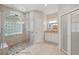 A stunning bathroom boasts a glass walk-in shower with pebble stone floor, a tile backsplash and dual vanities at 9491 Wickham Way, Orlando, FL 32836