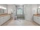 A luxurious bathroom features a glass walk-in shower with a stone pebble floor and dual sink vanities at 9491 Wickham Way, Orlando, FL 32836