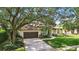 Attractive single-story home with a two-car garage, brick-lined driveway, and mature trees at 9491 Wickham Way, Orlando, FL 32836