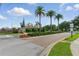 Landscaped neighborhood entrance featuring palm trees and brick-paved road under a blue sky at 9491 Wickham Way, Orlando, FL 32836
