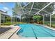 A beautiful screened in pool area featuring lush landscaping and a sparkling blue pool, perfect for relaxing and enjoying the outdoors at 9491 Wickham Way, Orlando, FL 32836