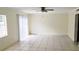 Bright vacant living room with white-tile floors, ceiling fan, and a sliding glass door at 1000 S Semoran Blvd # 415, Winter Park, FL 32792