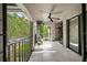 View of the covered tiled balcony featuring black railing and ceiling fan overlooking green landscaping at 1055 Kensington Park Dr # 203, Altamonte Springs, FL 32714
