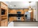Bright kitchen featuring wood cabinetry, stainless steel appliances, and a large black countertop at 1055 Kensington Park Dr # 203, Altamonte Springs, FL 32714