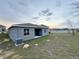 An ample backyard has a gray house and sunset on the horizon at 1147 Pomelo St, Davenport, FL 33837