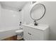 Modern bathroom with white vanity, round mirror, and a tub with white subway tile surround at 1235 Arapaho Trl, Geneva, FL 32732