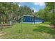 Home exterior featuring blue siding, green lawn, mature trees and a chicken coop at 1235 Arapaho Trl, Geneva, FL 32732